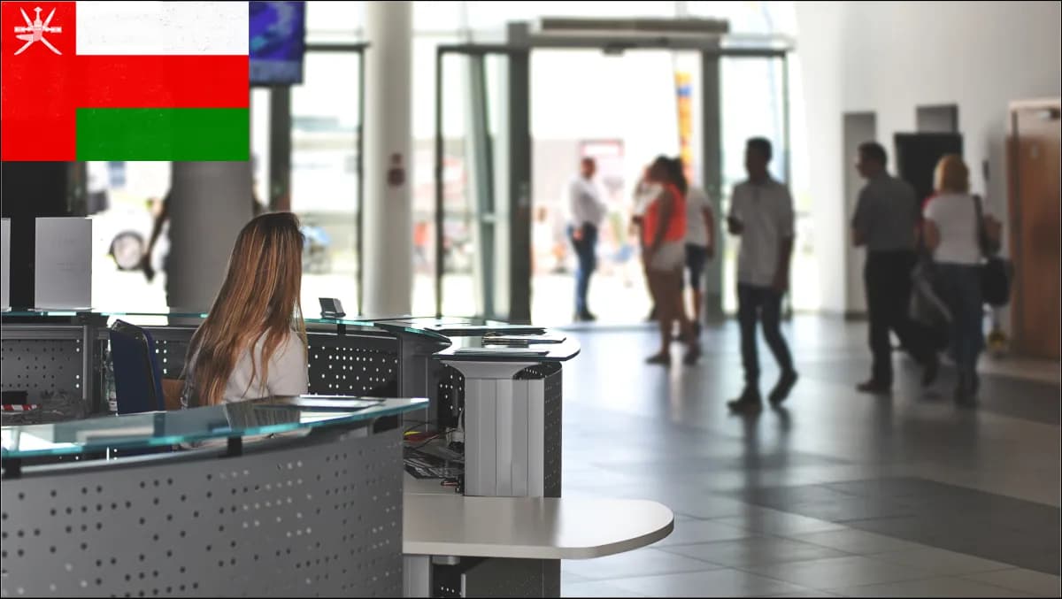 A bilingual Arabic and English visitor check-in kiosk in a Muscat corporate tower lobby with a contractor presenting an ID card.