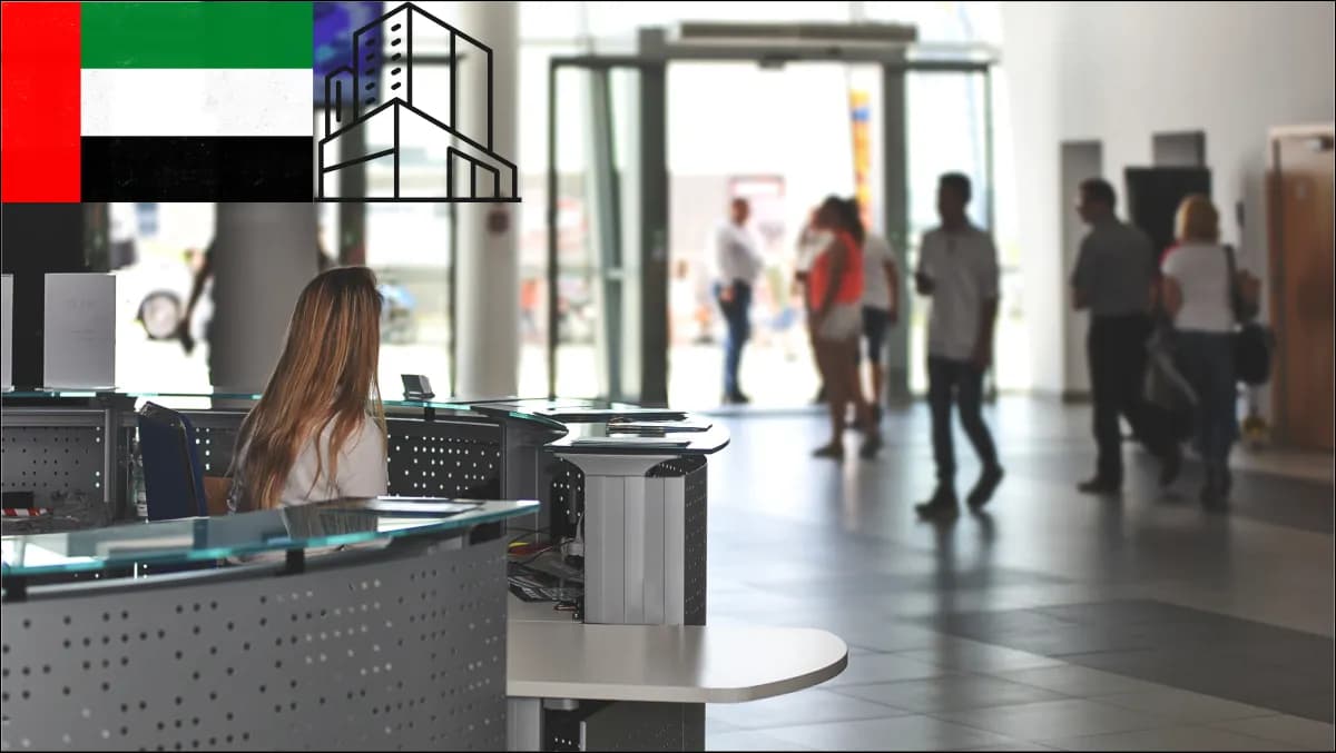 A reception desk in a multi-tenant Dubai tower with a bilingual visitor kiosk, badge printer and security-cleared turnstile.